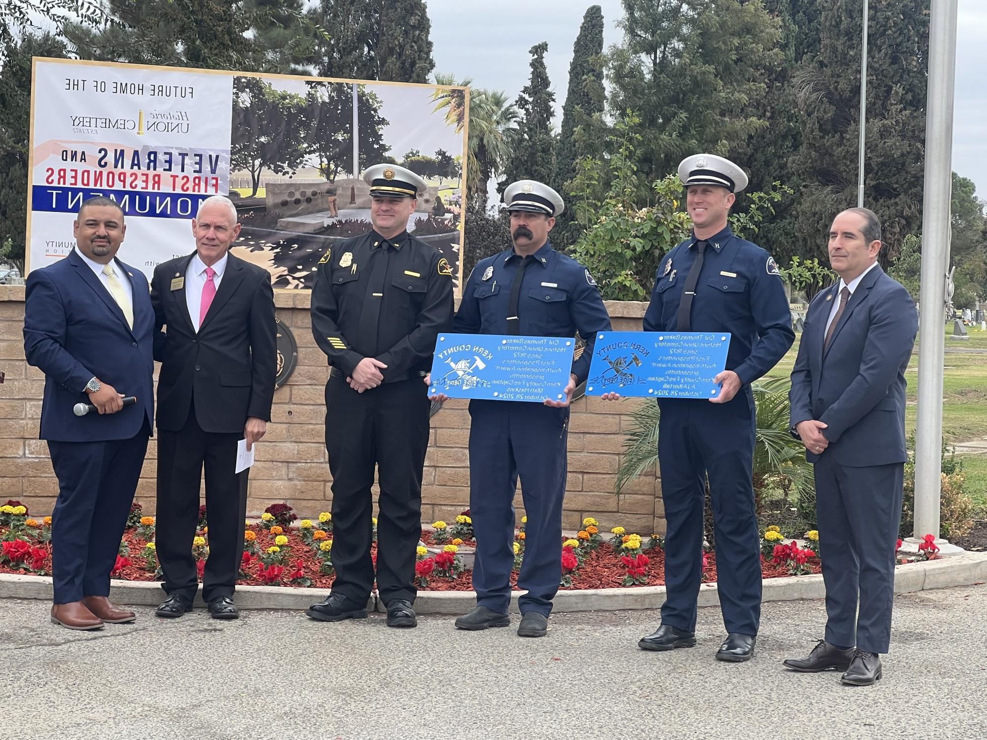 Kern County Fire Captains Matt Haskins and AJ Albertalli stand with their First Responder's Youth Inspiration Awards alongside Supervisor Jeff Flores, Fire Chief Aaron Duncan, cemetery trustee Dick Taylor, and Veterans Service Officer Jose Lopez.